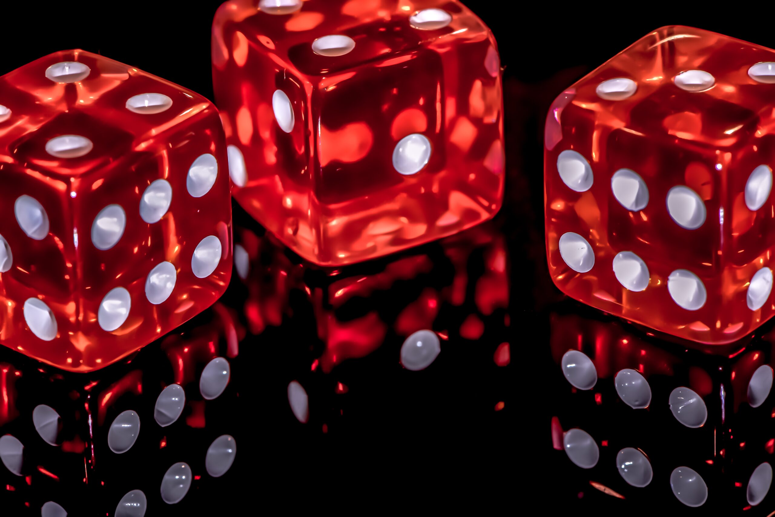 Photograph of three large red translucent dice against a black background.