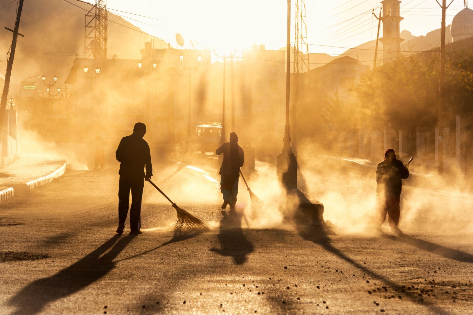 Image of four shadowy figures sweeping, cast in a golden light.