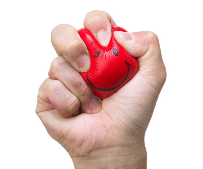 Image of a hand squeezing a red smiley face ball.