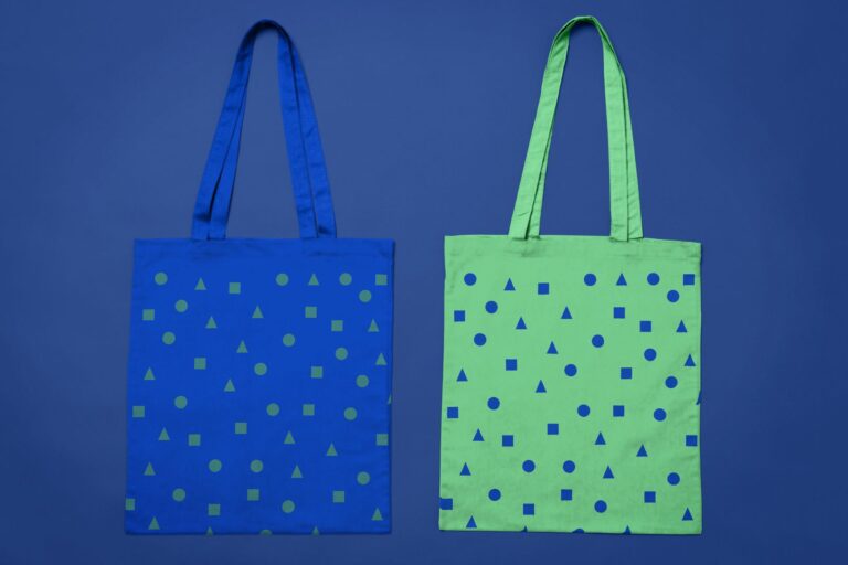 Photograph of two tote bags, one blue, one green, with corresponding patterns, against a dark blue background.