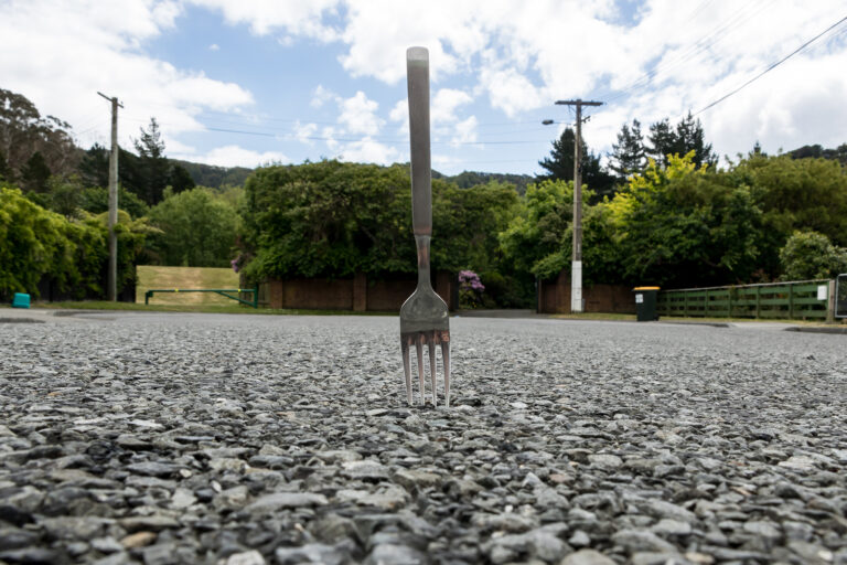 Image of a fork stuck in the pavement of a parking lot.