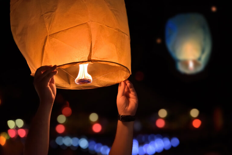 A photograph of a paper lantern being lit and launched in the air.