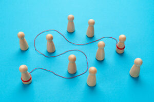 Photograph of a number of wooden pegs with a red string weaving between them, connecting two on opposite ends.