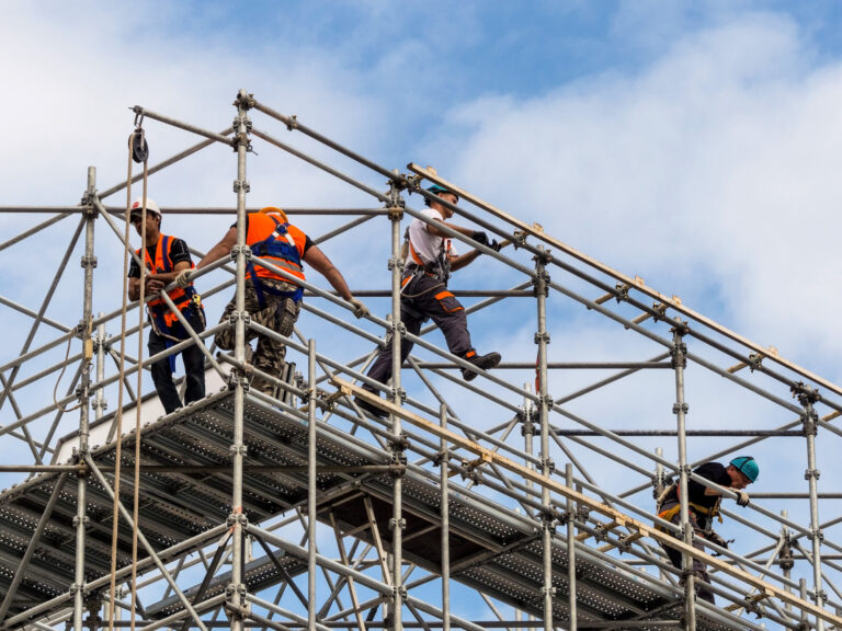 Photograph of some construction workers putting up scaffolding.