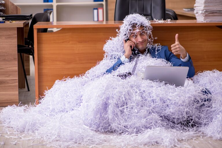 Photograph of a guy covered in a massive pile of shredded paper giving a thumbs up.