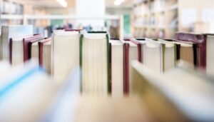 Photograph of rows of books on library shelves, taken through the stacks.