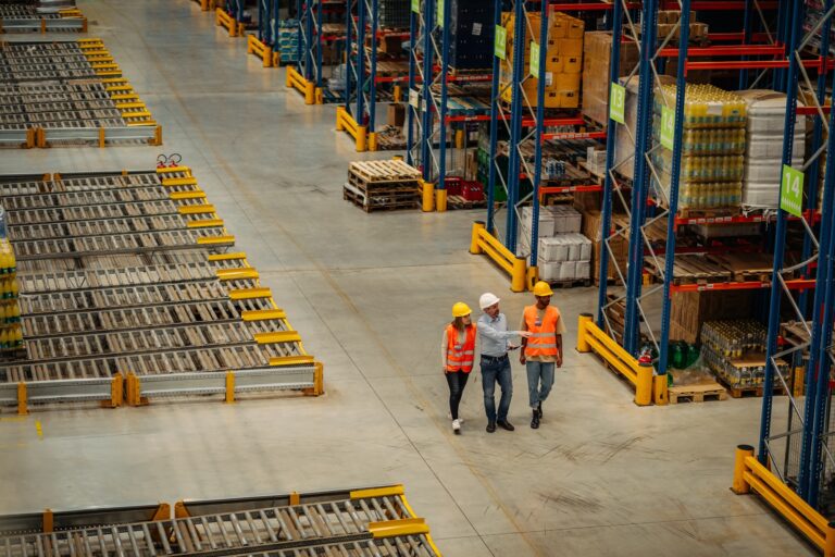 Photograph of three people in hard hats walking the floor of a warehouse.