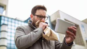 Image of a business bro-type guy looking at his phone and hyperventilating into a paper bag.