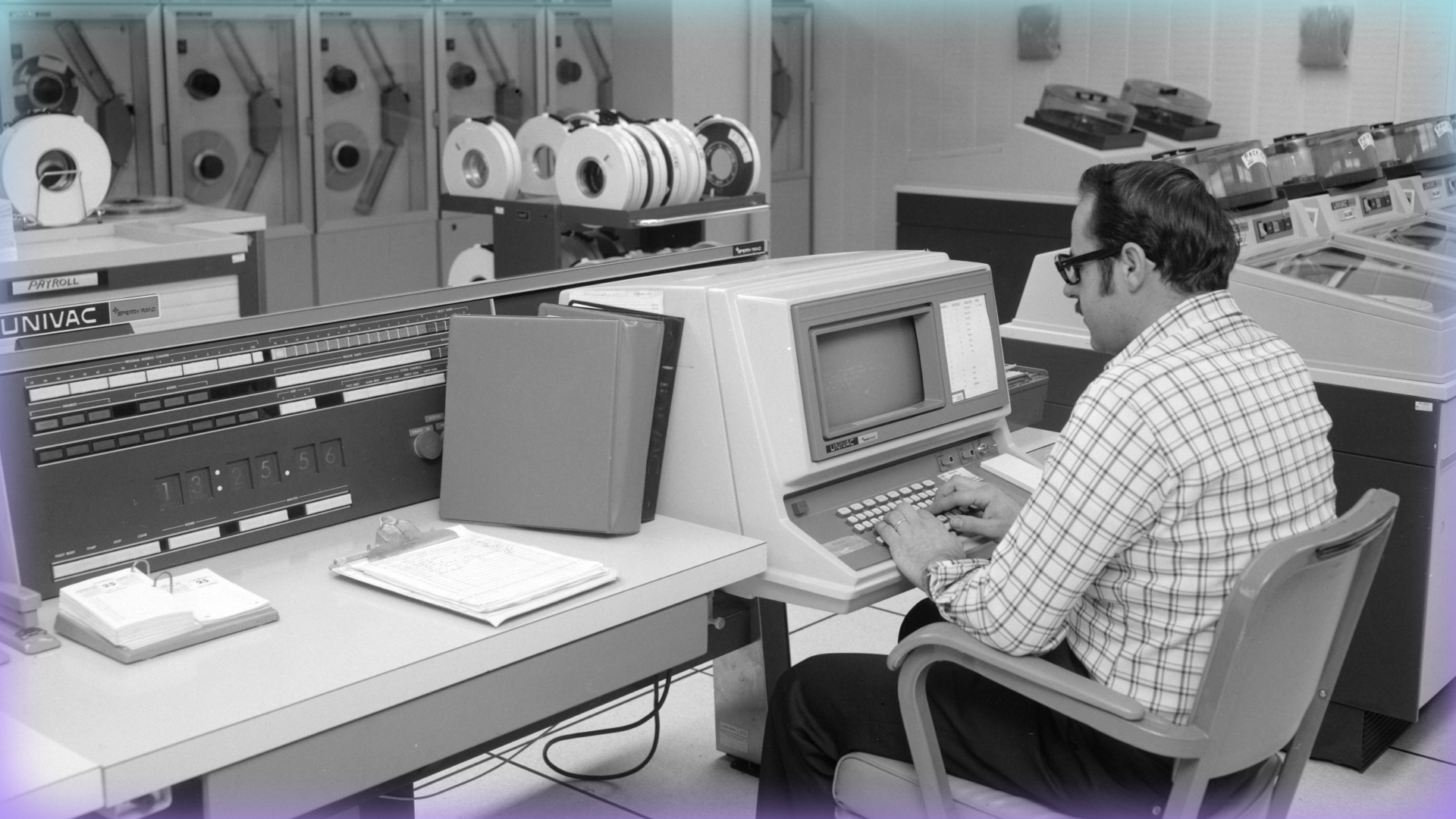 Black and white photograph of a man sitting at a UNIVAC 1106.