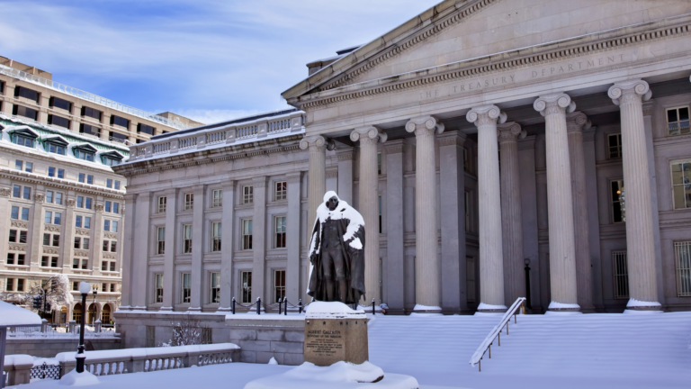 Image of the US Treasury building (with the statue of early Treasury Secretary Albert Gallatin in the foreground), the full tableau covered in snow.