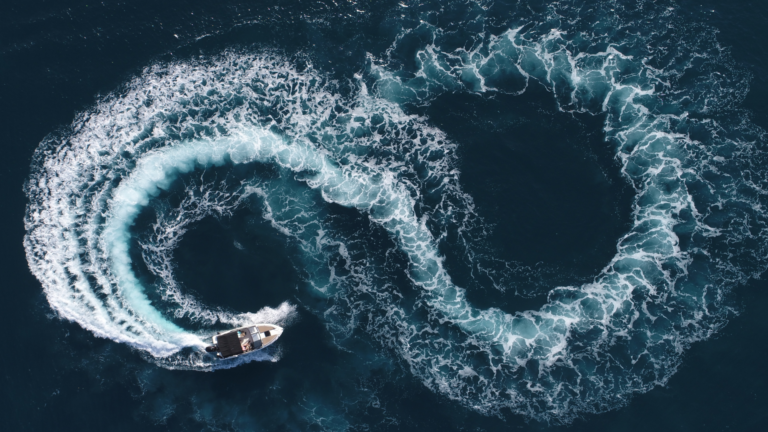 Aerial image of motor boat creating a figure 8 with its wake.