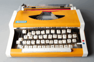Photograph of a yellow-orange typewriter with the keys somewhat askew.
