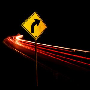 image of a right turn sign with the whooshing red lights of a vehicle zooming past, set against a black background.