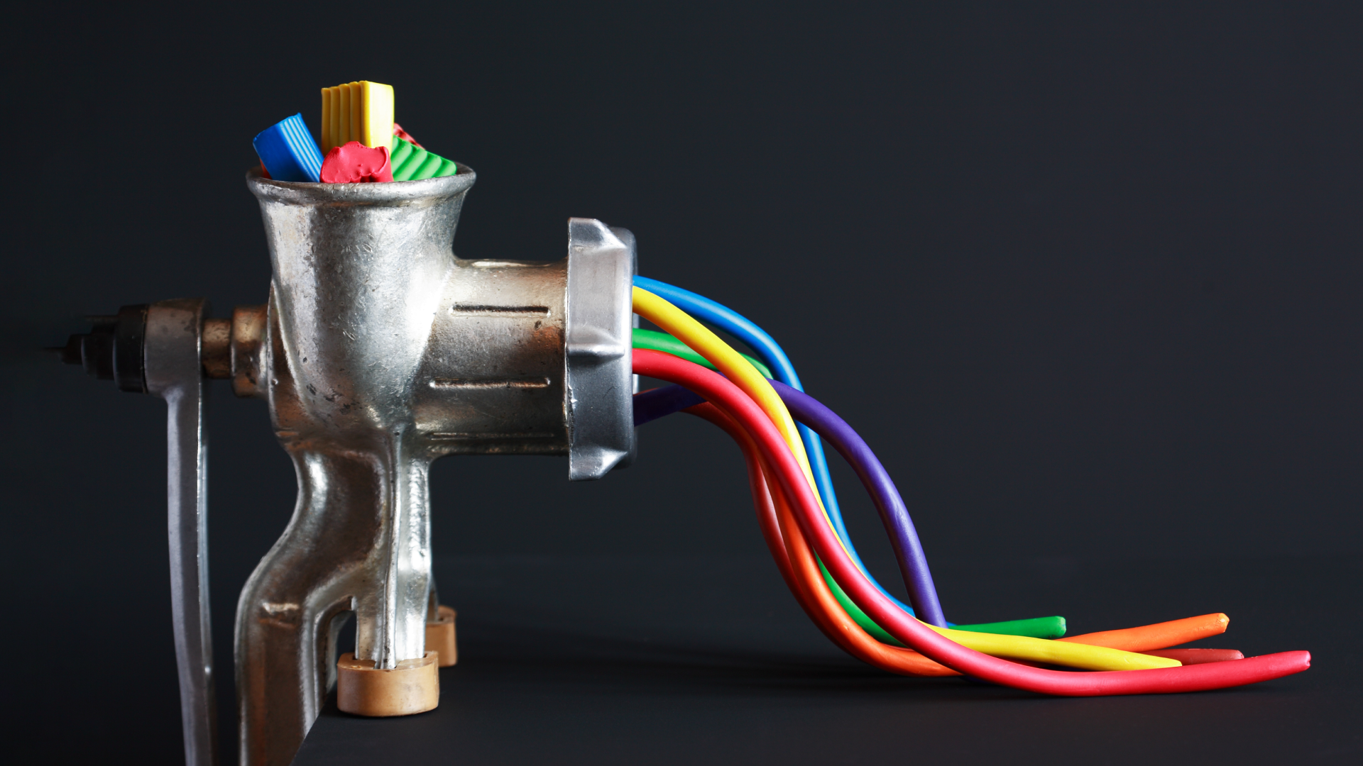 Image of colorful items being put into a grinder, with similarly colorful wires coming out.
