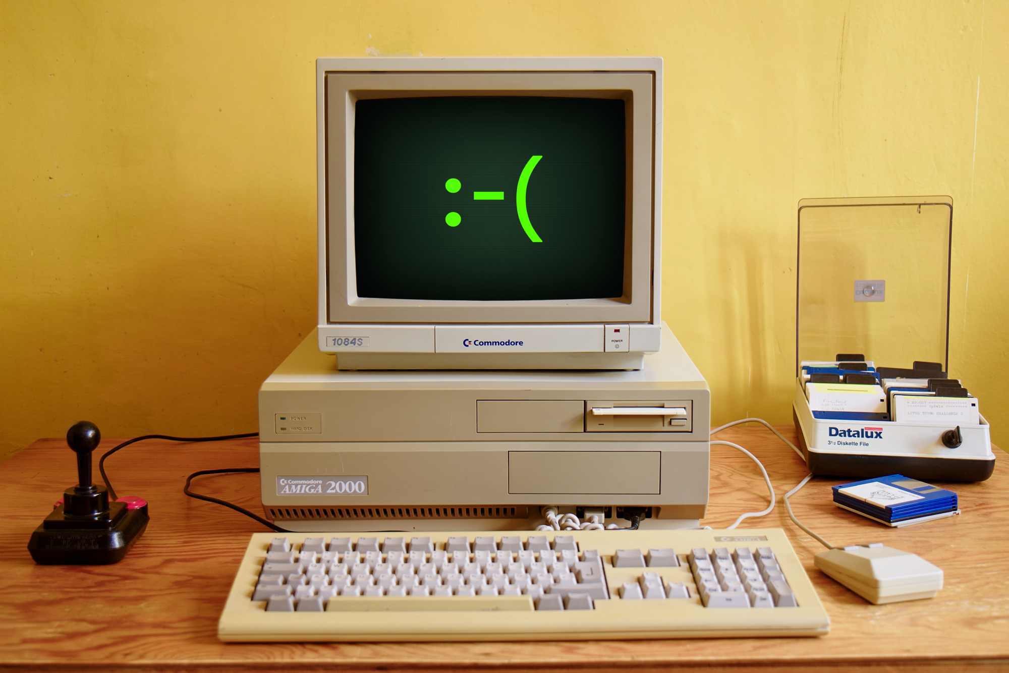 Image of an older computer with a green frowny face on the screen.