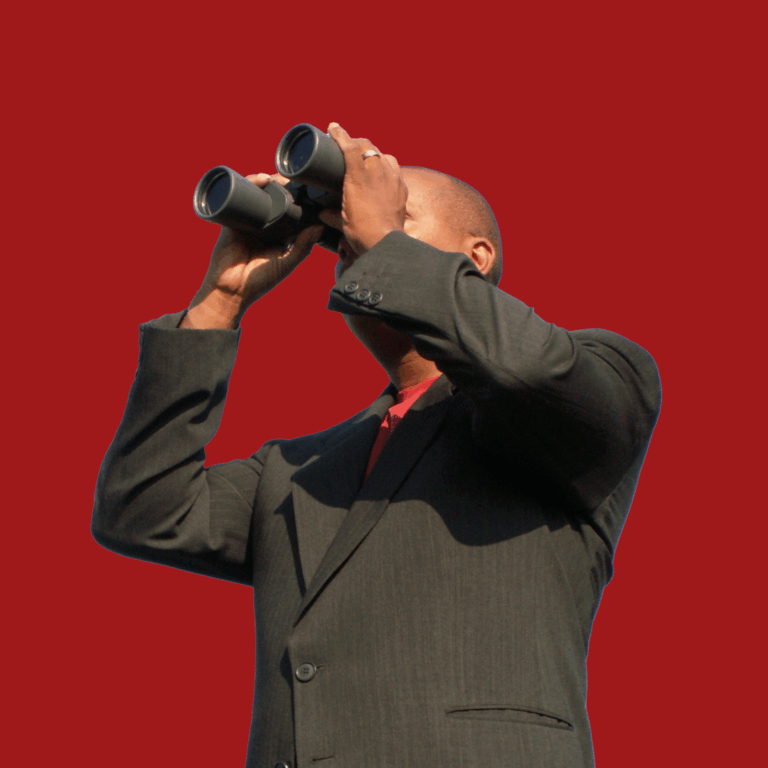 Image of a man in grey holding up a pair of binoculars, against a dark red background.