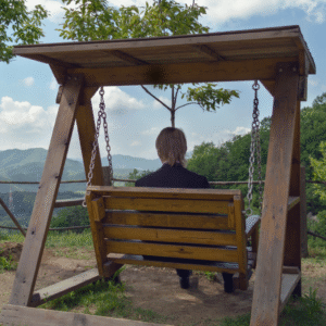 Image of a person in a business suit sitting on a wooden swing.