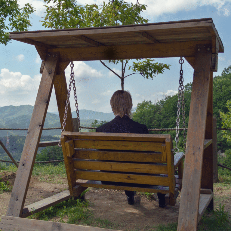 Image of a person in a business suit sitting on a wooden swing.