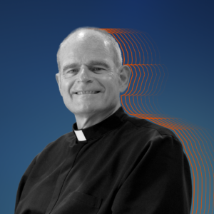 Black and white photo of Father Brendan, silhouetted by orange, against a dark blue background.