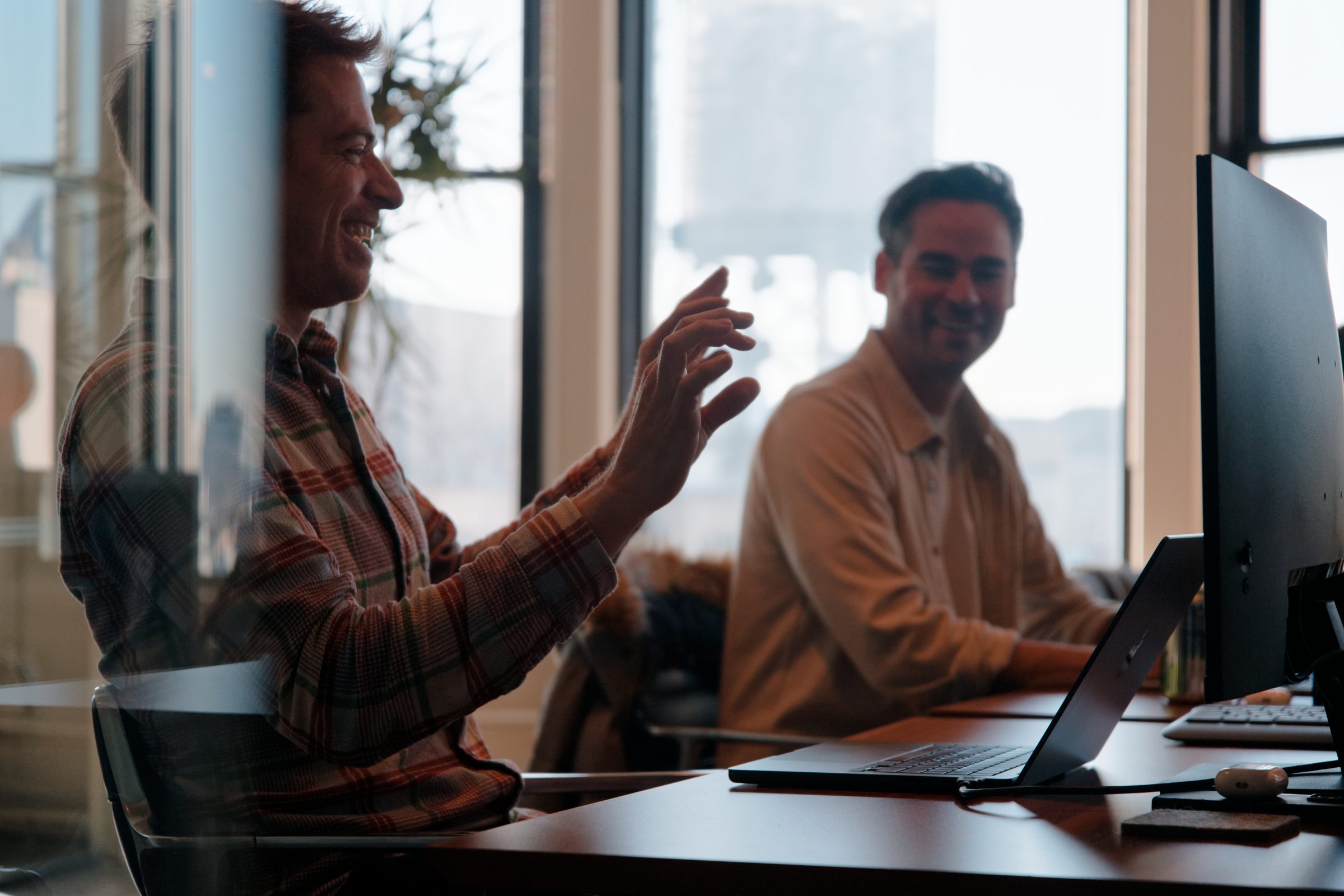 Two Aboard team members laughing together at their desks